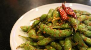 Plate of edamame topped with salted garlic chili oil and dried chilis sitting on top