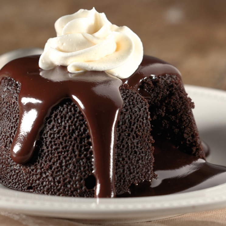 Close up of a chocolate lava cake with a dollop of whipped cream on top.