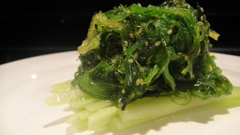 Closeup of Seaweed salad sitting on top of sliced cucumber