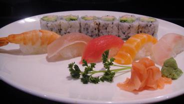 A plate with sushi rolls, various sashimi rolls, wasabi, and ginger.